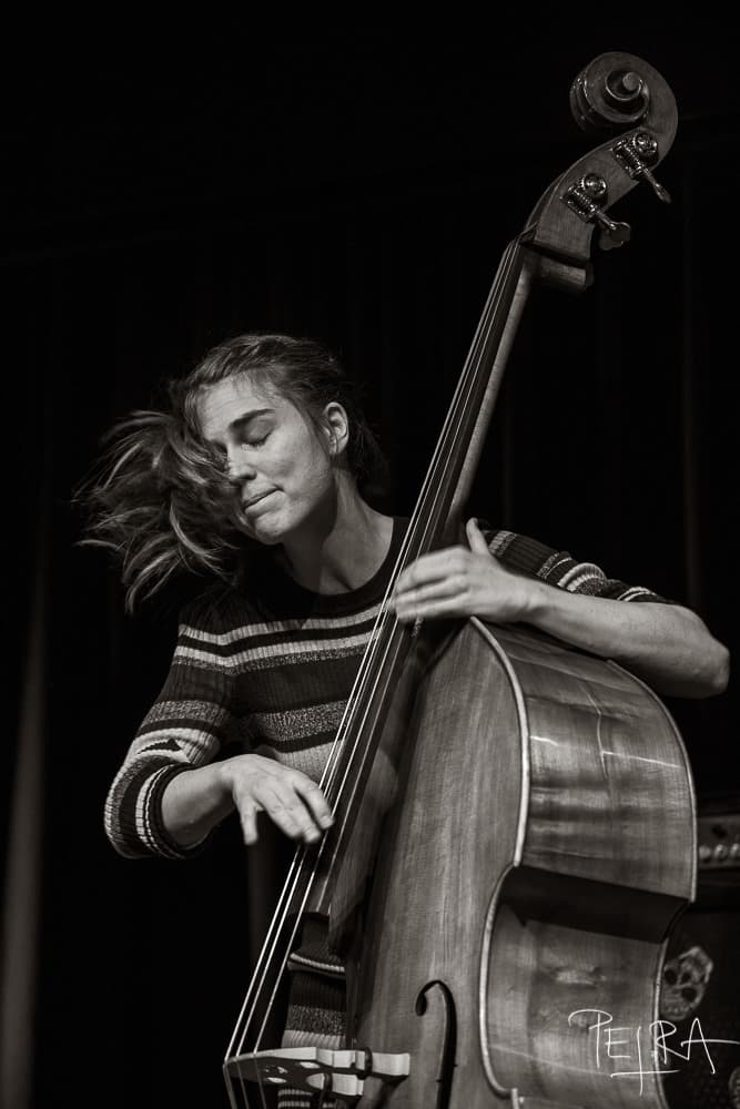 A person passionately playing an upright bass with eyes closed in a black and white setting.